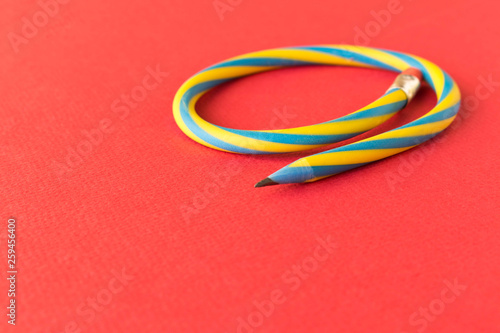 Flexible pencil . Isolated on red background. Bending pencil.