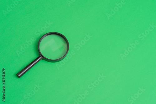 Magnifying glass on green background. Top view. Flat lay. Copy space. Concept