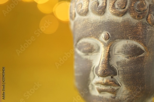Buddha's head on golden background with golden bokeh.Close up on the head of Buddha statue .The face of Buddha