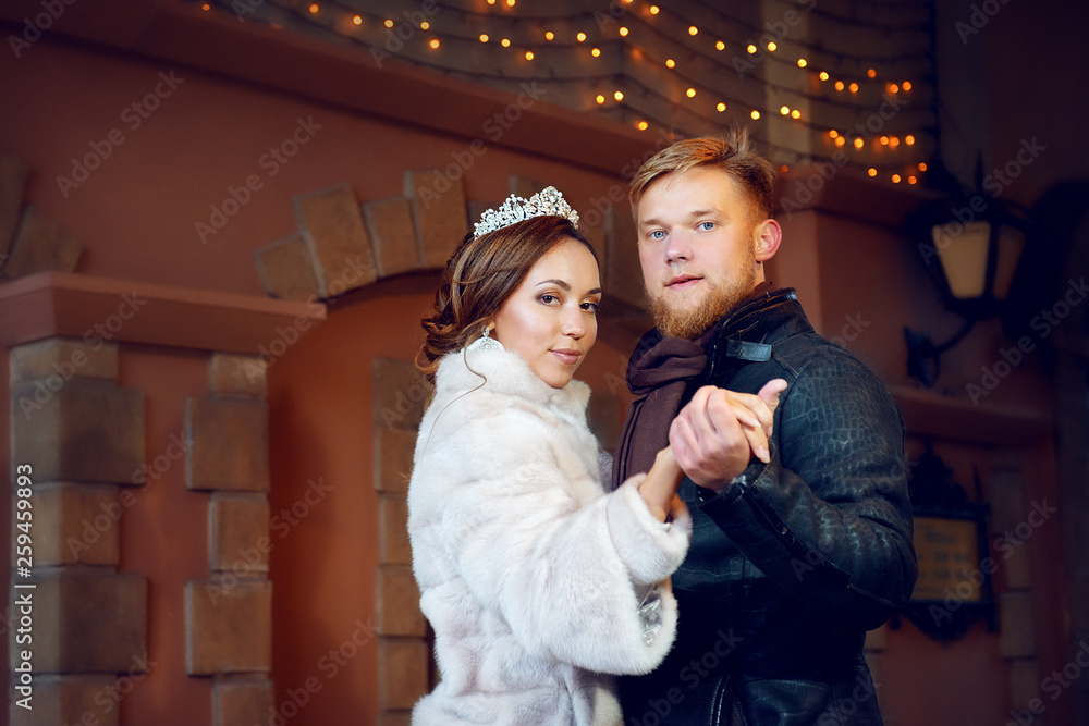 Portrait of the bride and groom in a dance position on a winter day against the background of a vintage wall with flashing garlands. Portrait of the bride and groom in a dance position on a winter day against the background of a vintage wall with flashing garlands.