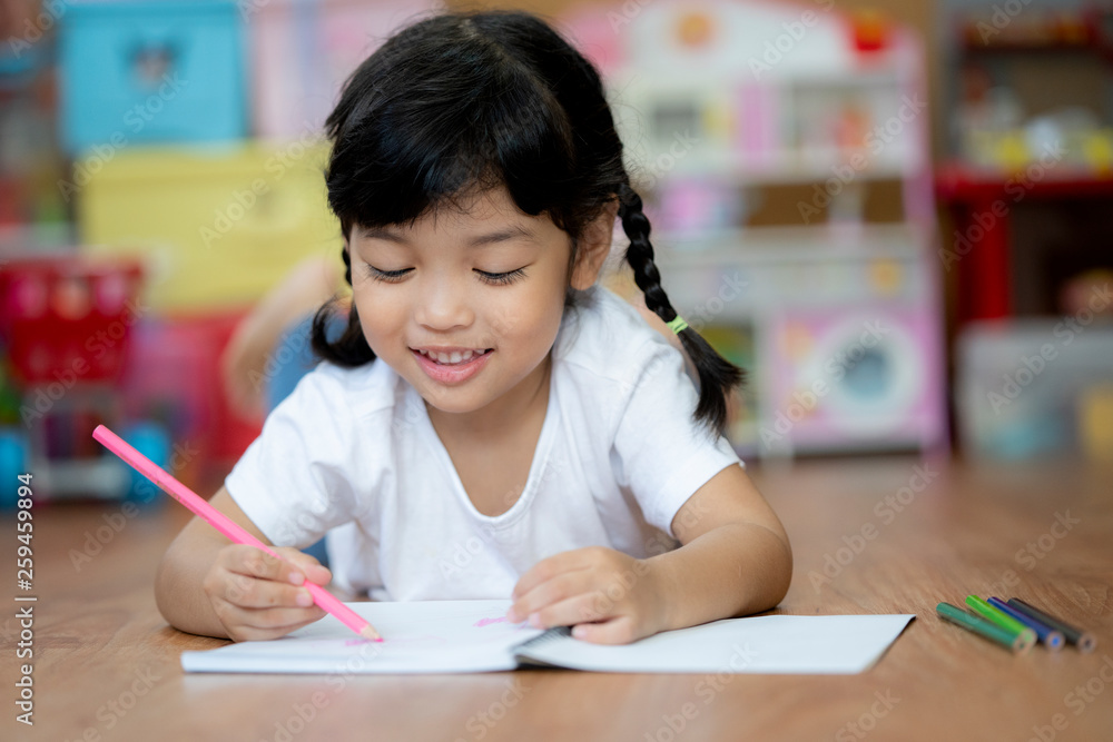 A cute child Asian girl doing homework and reading a book. Kid enjoy learning with happiness at home. Clever,Education and smart learning concept A cute child Asian girl doing homework and reading a book. Kid enjoy learning with happiness at home. Clever,Education and smart learning concept