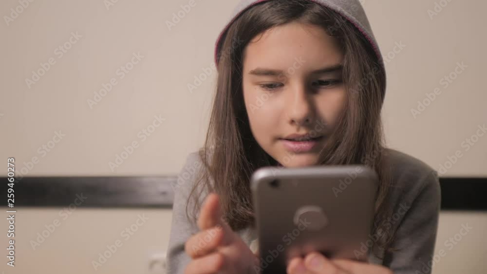 online shopping online retail service based . little teen girl in the hood writes a message chatting in social media messenger. children technology and communication concept lifestyle . teenage girl online shopping online retail service based . little teen girl in the hood writes a message chatting in social media messenger. children technology and communication concept lifestyle . teenage girl