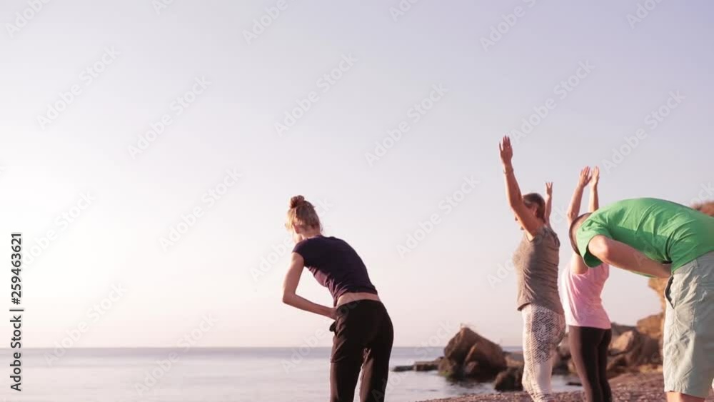 Yoga class group adult women and one man practice yoga and do breathing exercises with instructor on the beach at sunrise. Wellbeing, wellness, fitness, sport, yoga and healthy lifestyle concept, full Yoga class group adult women and one man practice yoga and do breathing exercises with instructor on the beach at sunrise. Wellbeing, wellness, fitness, sport, yoga and healthy lifestyle concept, full