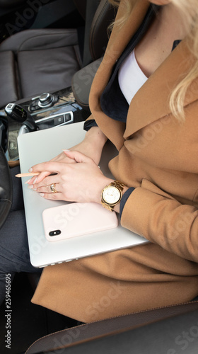 Young woman holding a phone. Workplace in car with laptop. Close up 