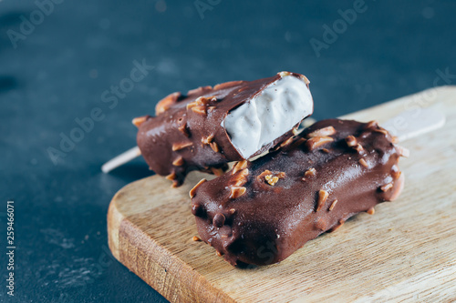 Eskimo on stick ice cream in chocolate glaze with nurs on stone background. Yummy sweet food snack treat. Close-up, copy space photo