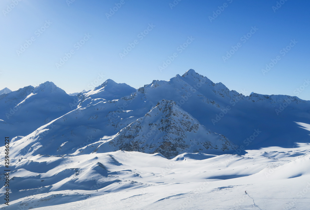 Snowy peaks of Caucasian Mountains in the blue sky. Elbrus region Snowy peaks of Caucasian Mountains in the blue sky. Elbrus region