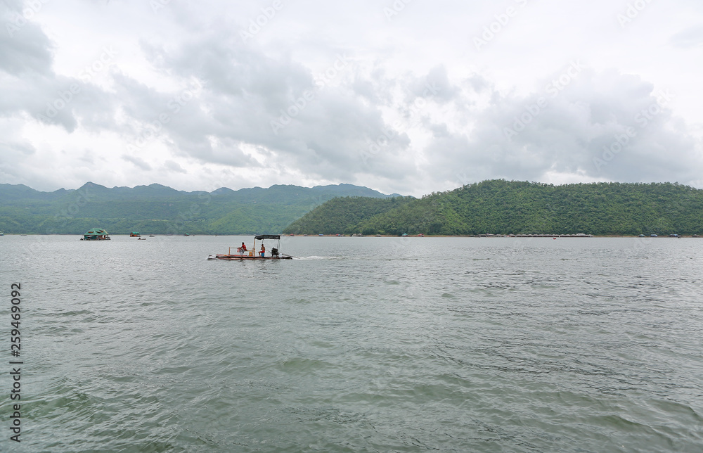 Landscape view of fishing boat in the lake with mountain at kanchanaburi, Thailand.