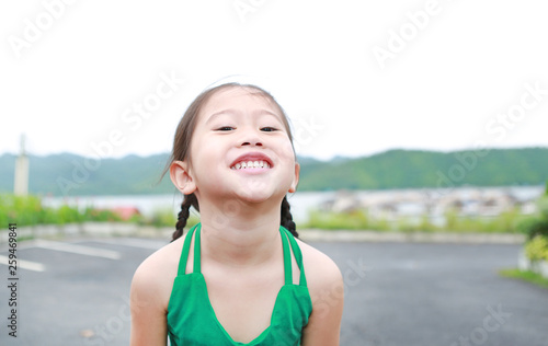 Portrait of happy Asian child girl relaxes in hillside.