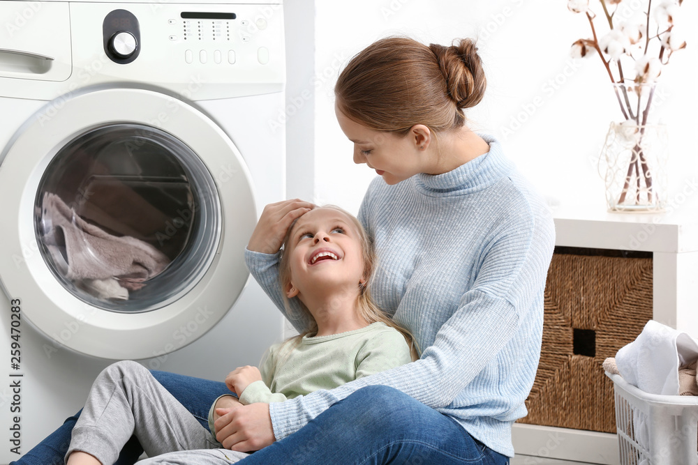 Young woman and her little daughter doing laundry at home Young woman and her little daughter doing laundry at home