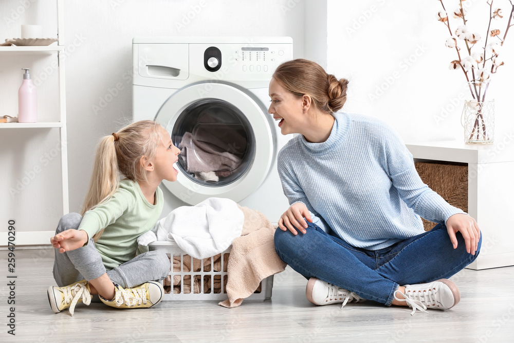Young woman and her little daughter playing at home on laundry day Young woman and her little daughter playing at home on laundry day