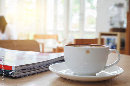 Cup of Hot Latte Coffee on wood table with light window.