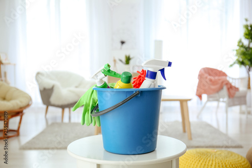 Bucket with cleaning supplies on table at home