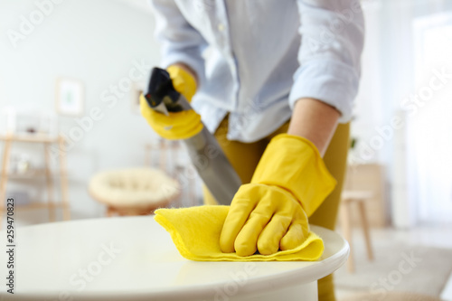 Young woman cleaning table at home, closeup