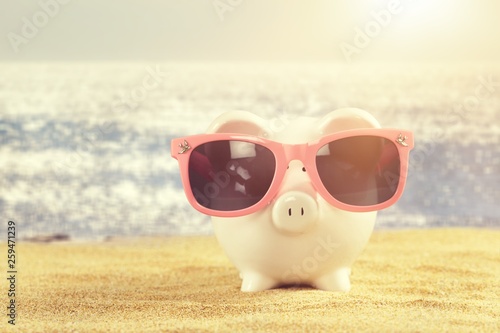 Summer piggy bank with sunglasses on the beach © BillionPhotos.com