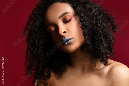 Portrait of beautiful African-American woman with unusual makeup on color background