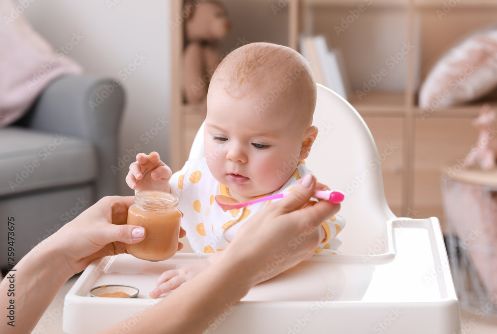 Mother feeding her little daughter at home