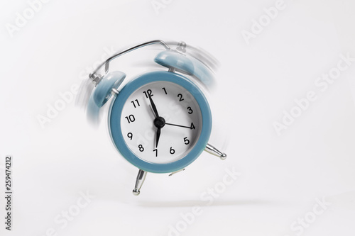 The blue morning alarm rings and jumps on a gray background.