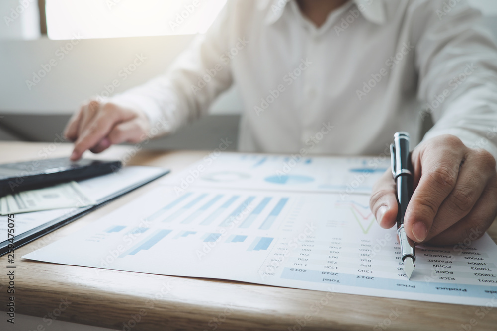 Finances Saving Banking Concept, Man accountant calculations income and analyzing financial graph data with calculator Finances Saving Banking Concept, Man accountant calculations income and analyzing financial graph data with calculator