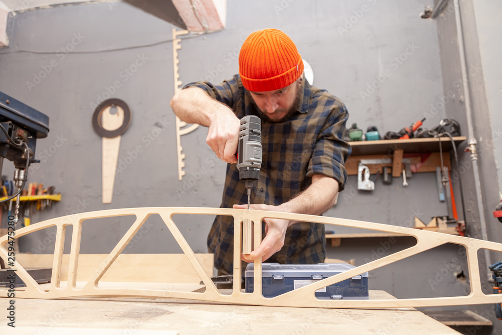 Home repair concepts, close up. Handicraft Carpentry. Cabinet-maker hands drilling a wooden plank using screwdriver on the working table in the workshop Home repair concepts, close up. Handicraft Carpentry. Cabinet-maker hands drilling a wooden plank using screwdriver on the working table in the workshop