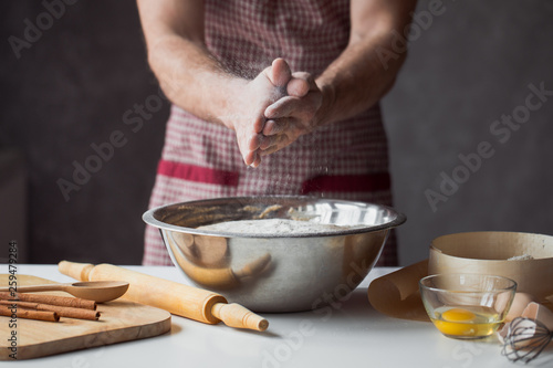 A handful of flour with egg on a rustic kitchen. Against the background of men's hands