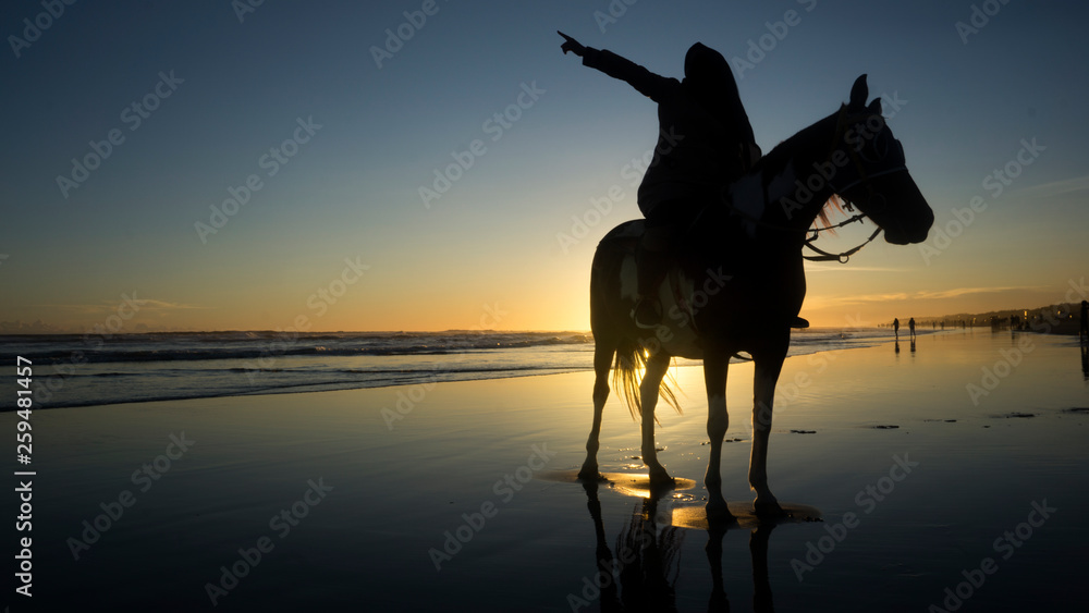 silhouette of muslim women who are riding horses on the beach with the atmosphere of the sunset silhouette of muslim women who are riding horses on the beach with the atmosphere of the sunset