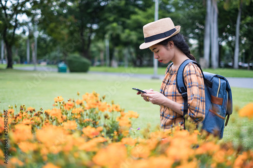 Asian women tourists backpack are follow us online social news with smartphone at flowers garden. traveling in the holidays.