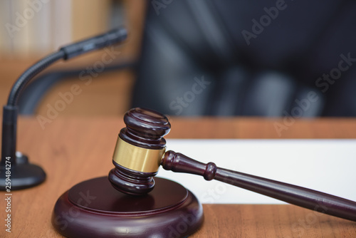 Court, courtroom, wooden hammer. Wooden table, books, microphone on the table of the judge. Court hearing.