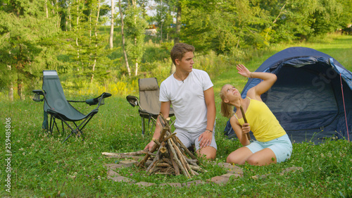 Quadro em tela Man and woman on fun camping trip trying to swat the bugs flying around them