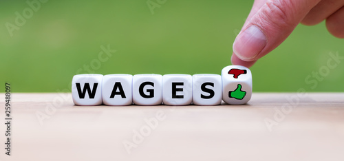 Symbol about job satisfaction. Dice form the word "wages" and a hand turns a dice and changes a thumbs down symbol to a thumbs up symbol.