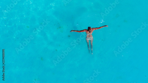 Travel and vacation background Woman in swimsuit swims in the crystal clear turquoise water. Aereal view