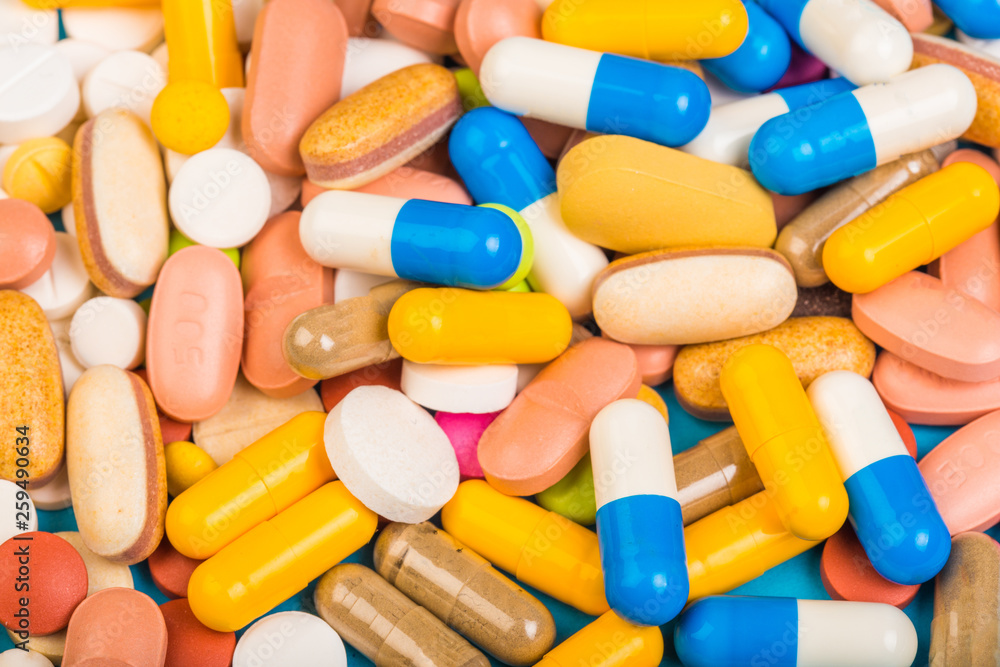 set of multi-colored tablets and capsules on a blue background set of multi-colored tablets and capsules on a blue background