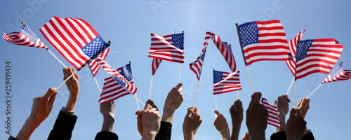 Group of People Waving American Flags over blue sky