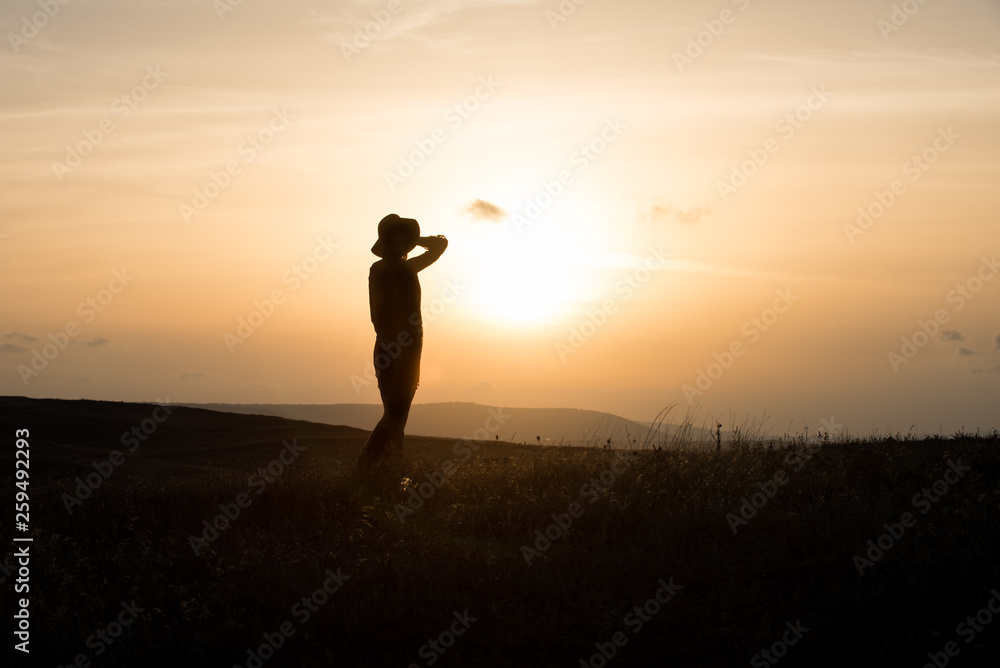 Woman with hat silhouette at sunset