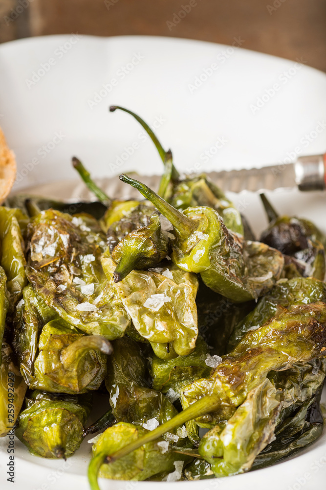 Green Padron Peppers with Crisp Bread in Rustic White Plate. Pimientos de Padrón. Green Padron Peppers with Crisp Bread in Rustic White Plate. Pimientos de Padrón.