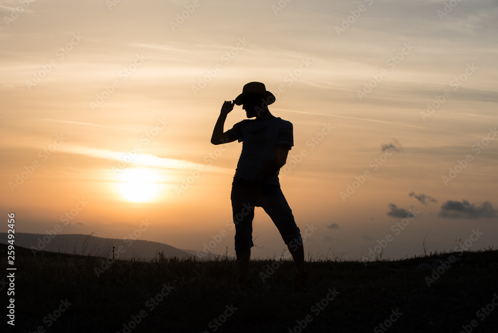 Man dancing with hat silhouette at sunset