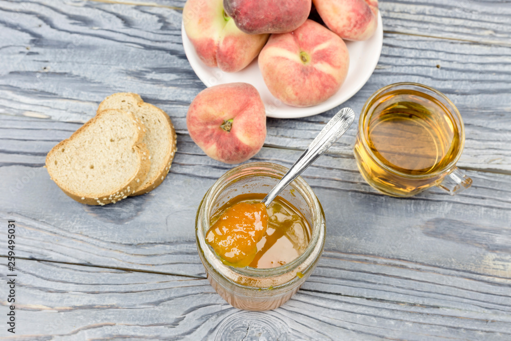 Peach jam, tea and bread close-up on a wooden table Peach jam, tea and bread close-up on a wooden table