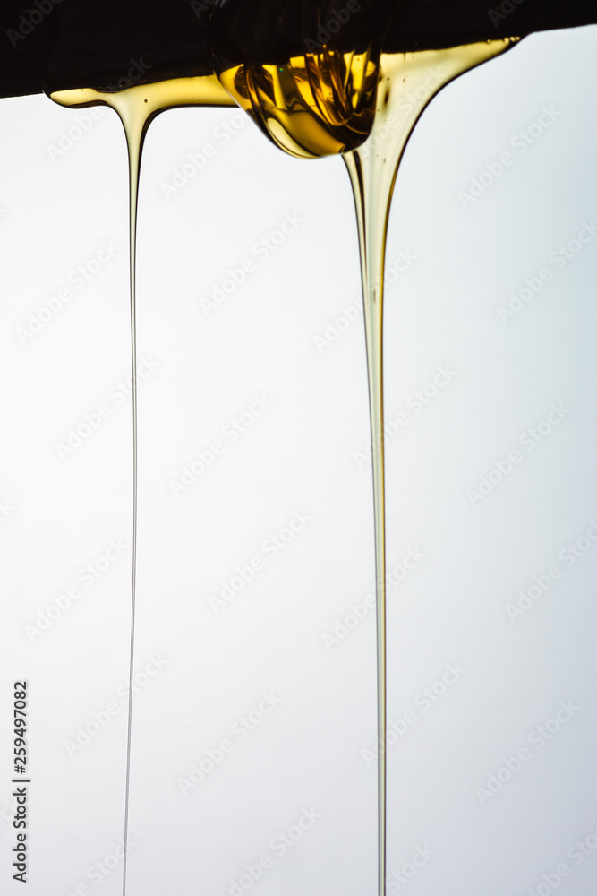 Pouring honey or golden liquid on white background. Pouring honey or golden liquid on white background.