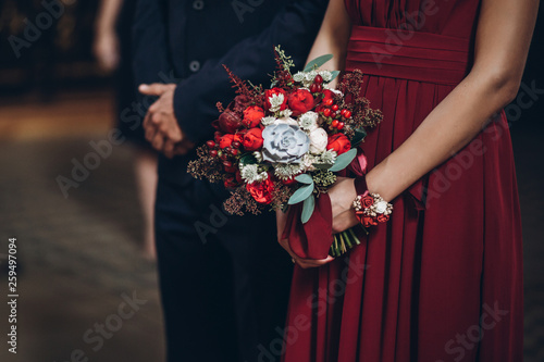 bridesmaid holding rustic bouquet with groomsman, couple in church during wedding ceremony, religion traditions