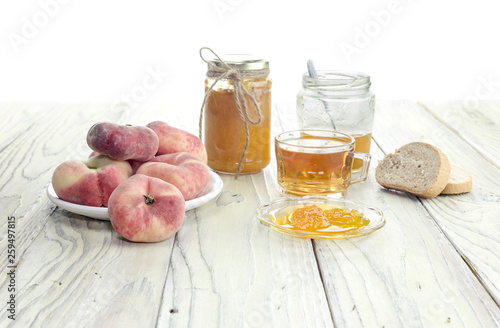 Peach jam, tea and bread close-up on a wooden table