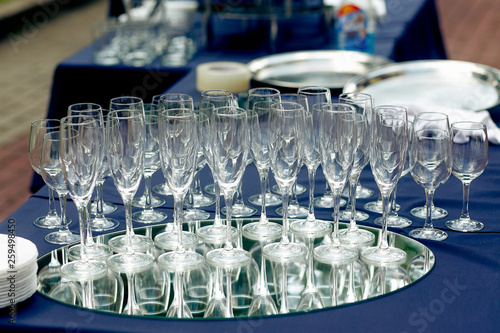 champagne glasses on table at wedding reception outdoors. empty glasses for champagne drinks on tray at celebration in park.