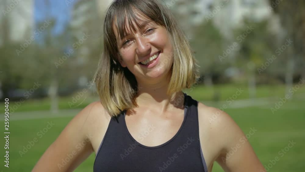 Smiling young woman with piercing looking at camera. Closeup shot of happy young sporswoman posing in summer park. Happiness concept Smiling young woman with piercing looking at camera. Closeup shot of happy young sporswoman posing in summer park. Happiness concept