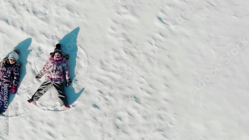 Aerial view from above of children lying on white snow