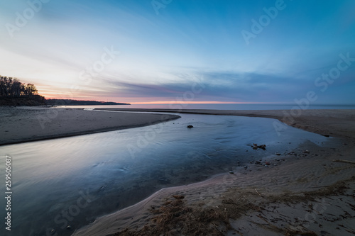 Wide and shallow stream on the shore of the Baltic sea at sunset