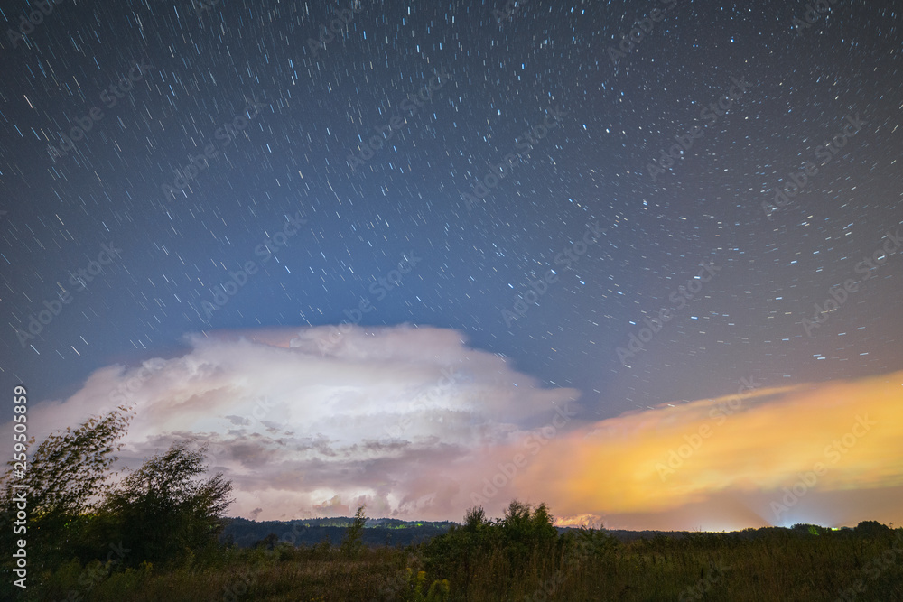 Powerful thunderstorm with lightnings at night with starry sky on the background Powerful thunderstorm with lightnings at night with starry sky on the background