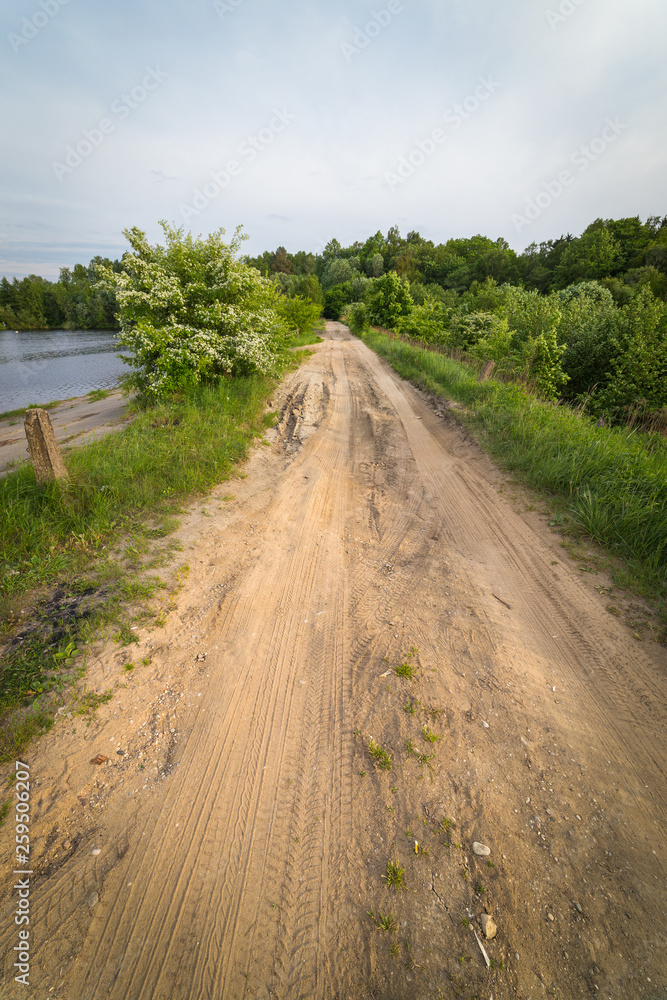 Dirt road on the edge of the old dam. Calm spring evening Dirt road on the edge of the old dam. Calm spring evening