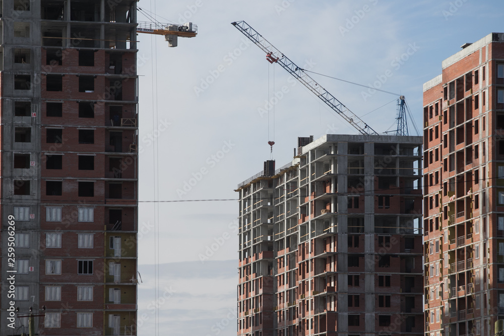 Construction of a multi-storey residential complex. Crane near the building under construction. Background construction site. Construction of a multi-storey residential complex. Crane near the building under construction. Background construction site.