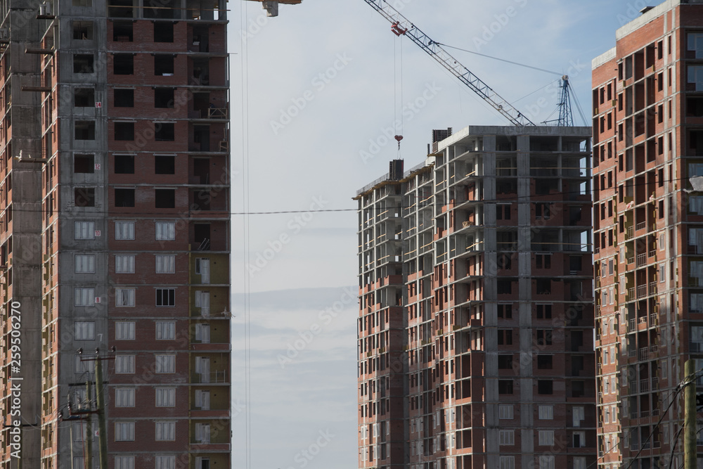 Construction of a multi-storey residential complex. Crane near the building under construction. Background construction site. Construction of a multi-storey residential complex. Crane near the building under construction. Background construction site.