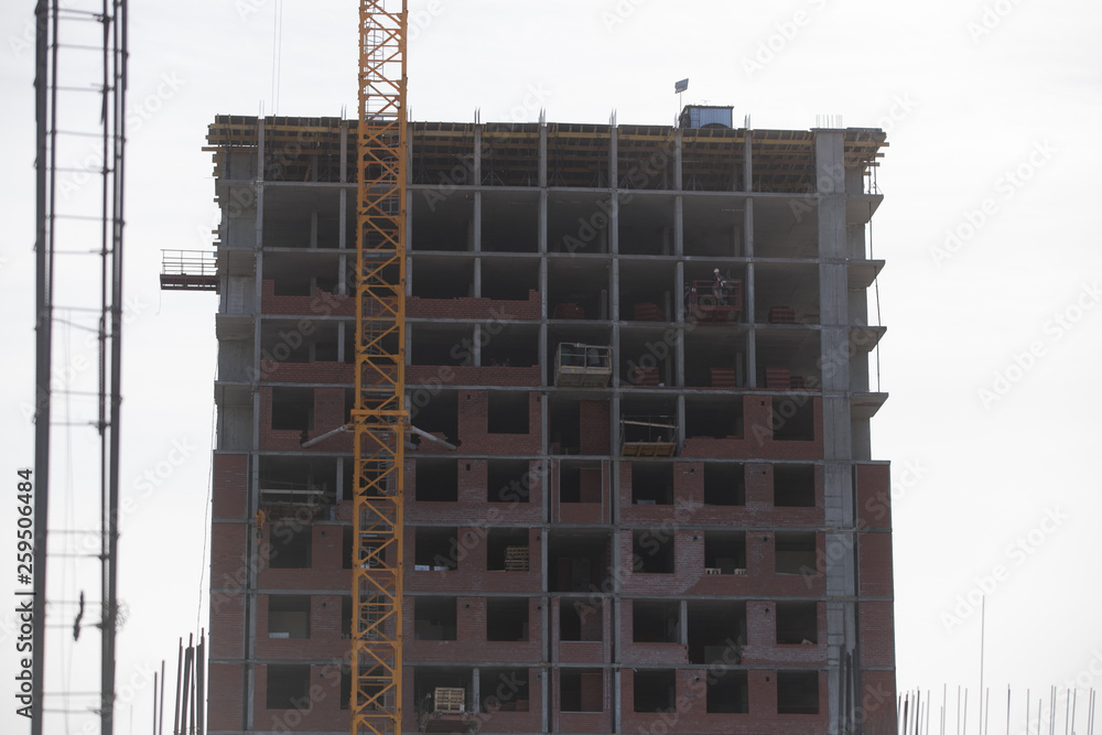 Construction of a multi-storey residential complex. Crane near the building under construction. Background construction site. Construction of a multi-storey residential complex. Crane near the building under construction. Background construction site.