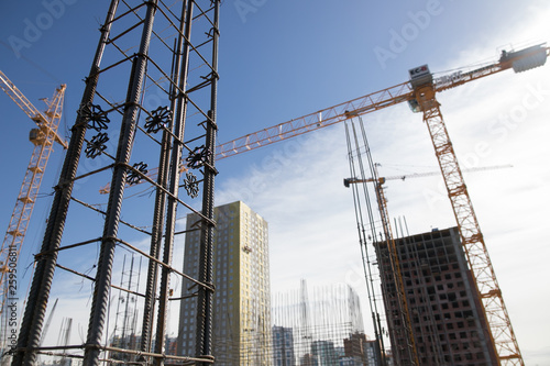 Concrete pillars on construction site. Building of skyscraper with crane, tools and reinforced steel bars.