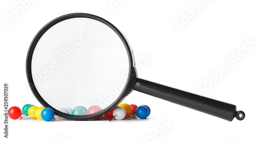 Magnifying glass looking at closeup of push pin tacks